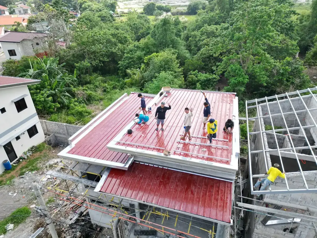Aerial view of the STS crew installing mounting rails on a red metal roof