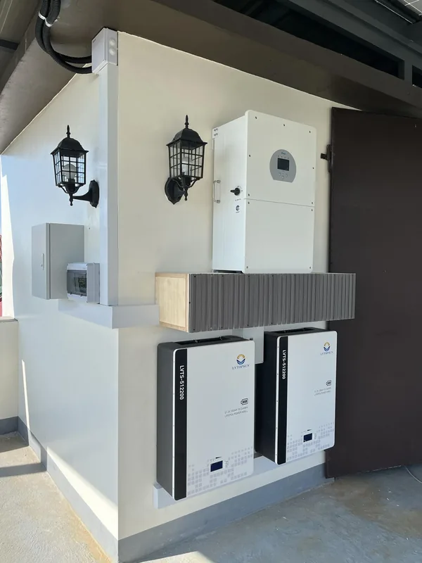 Hybrid inverter and two battery cabinets on an outdoor wall between wall lamps