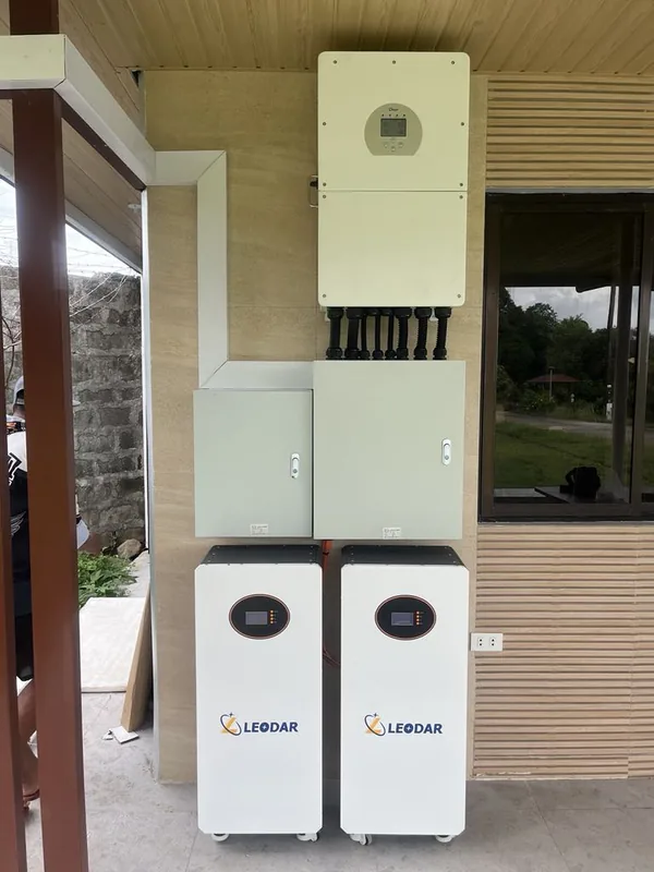 Hybrid inverter, two protection enclosures and two battery cabinets beside wooden slats
